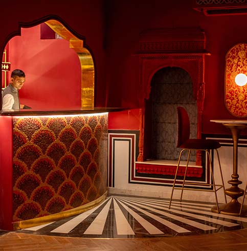 Close-up of the crimson bar interior with scalloped arch mirror and brass details