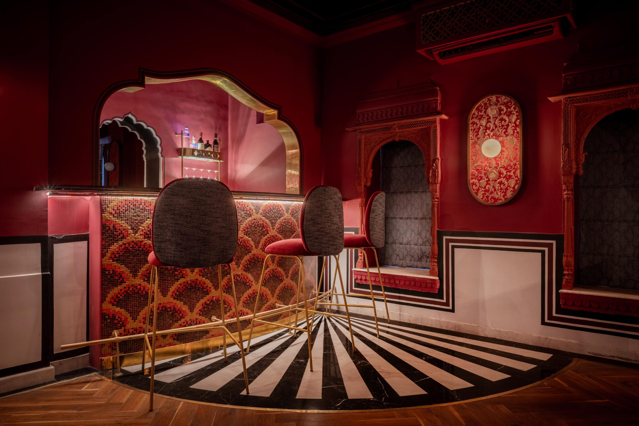 The crimson bar at Padmaa — fish-scale mosaic counter, brass stools, striped marble floor