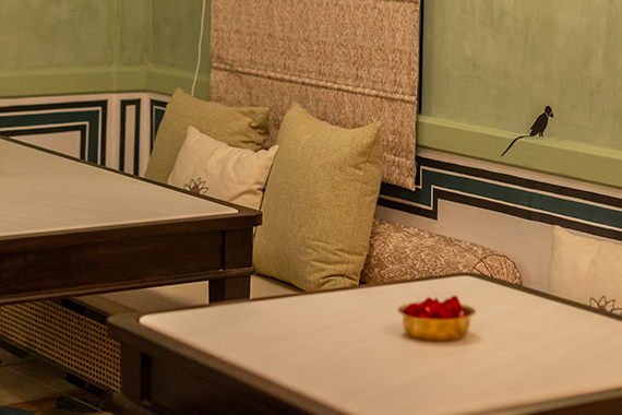 Padmaa restaurant — heritage seating with cushions, bird mural, rose petals